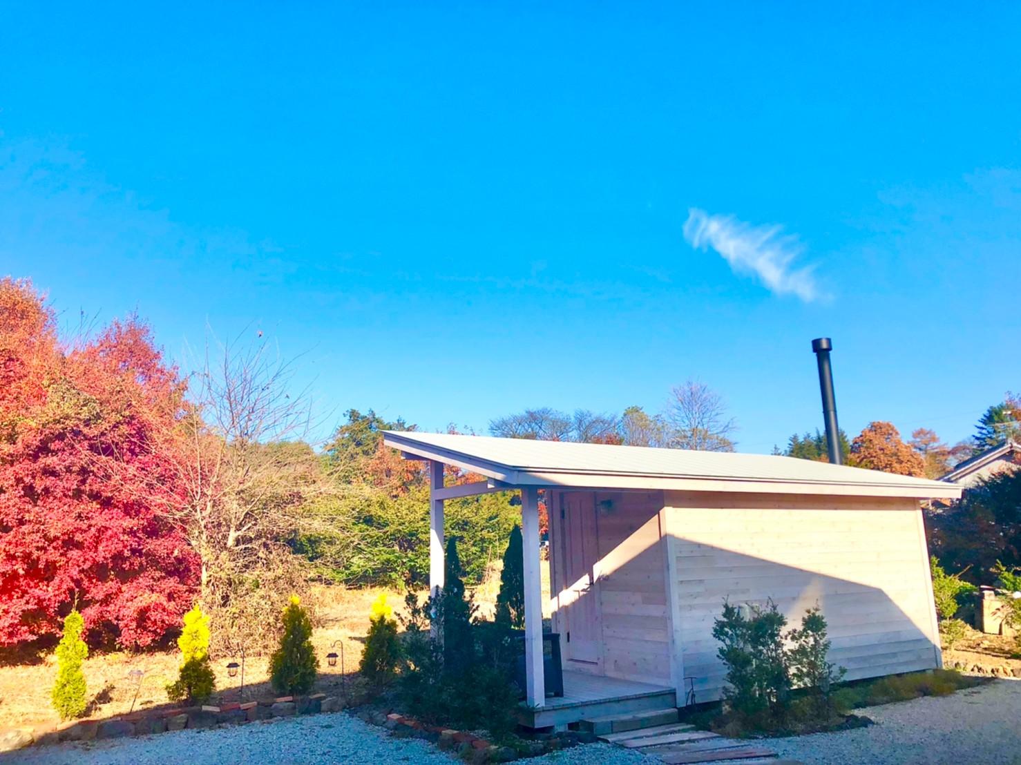 紅葉の中に建つ白い小屋の外観
