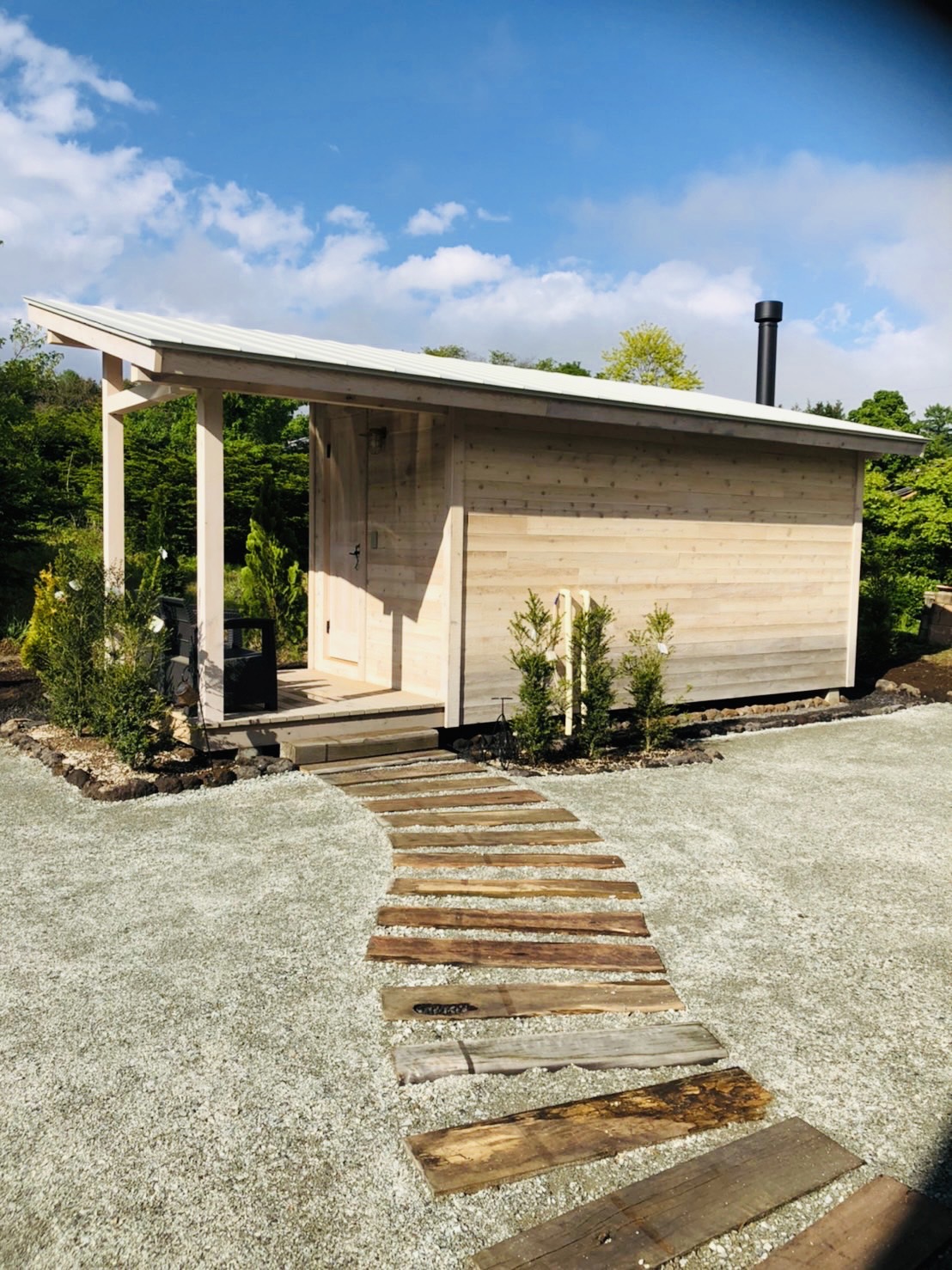 木のサウナ小屋の外観と石畳の小道