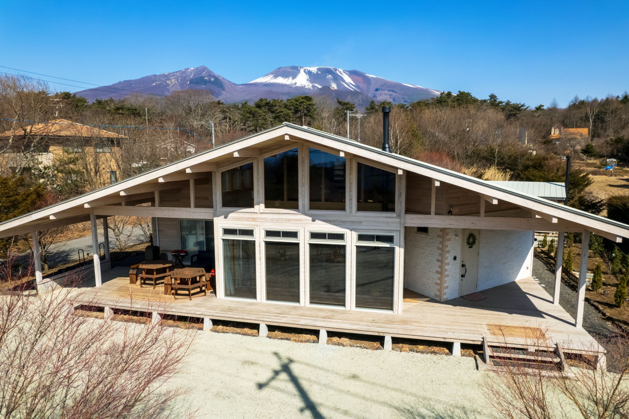 雪山を背景に大きな窓が並ぶ平屋の外観